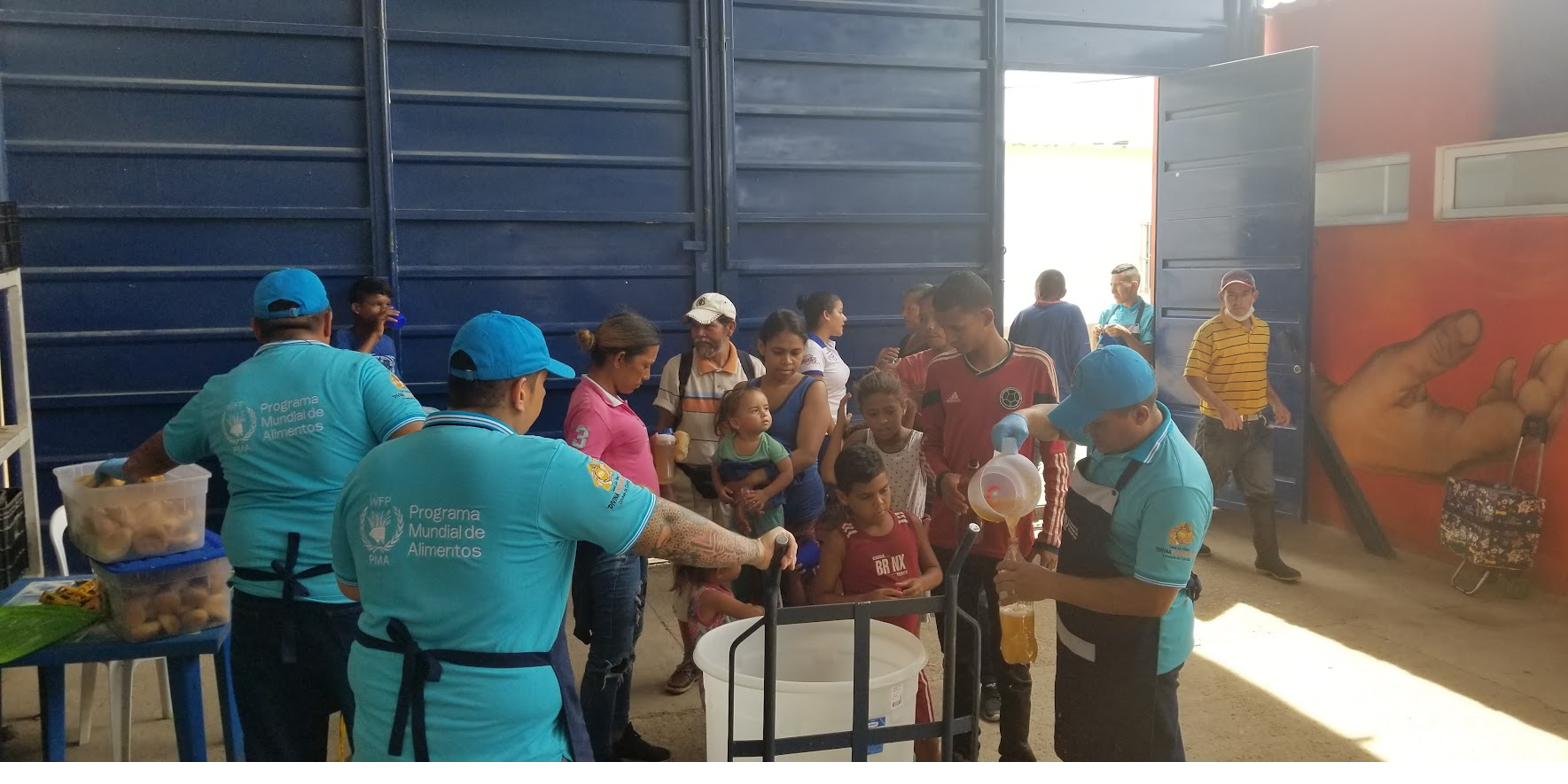 Volunteers and partner staff distributing clean water to families lined up with containers.
